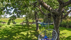 A hammock hanging from a tree in a grassy outdoor area with benches and a picnic table in the background. - Pet friendly home in Warnoleka with WiFi (Warnoleka)