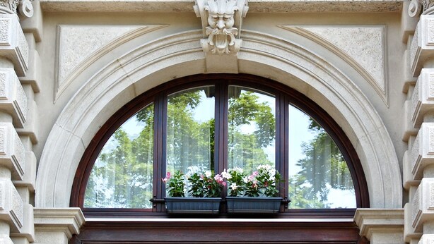Ein Fenster mit einem steinernen Bogen und einem Blumenkasten.