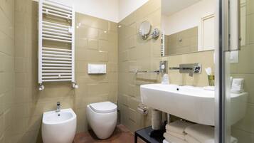 A modern bathroom with a bidet, toilet, and a large sink with a mirror above it.