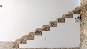 Eine Treppe mit Steinpodesten, die zu einer weißen Wand führt.