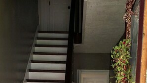 A staircase with wooden steps and a wooden handrail, leading to a door with a decorative plant beside it.