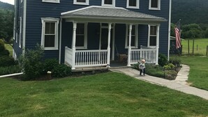 A two-story house with a porch and a small garden.