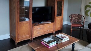 A living room with a wooden cabinet, a television, and a coffee table with books.