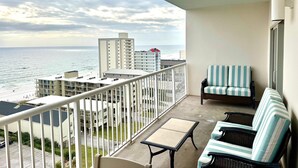 Ein Balkon mit Blick auf das Meer, eine Sitzecke mit gestreiften Kissen und ein kleiner Tisch.