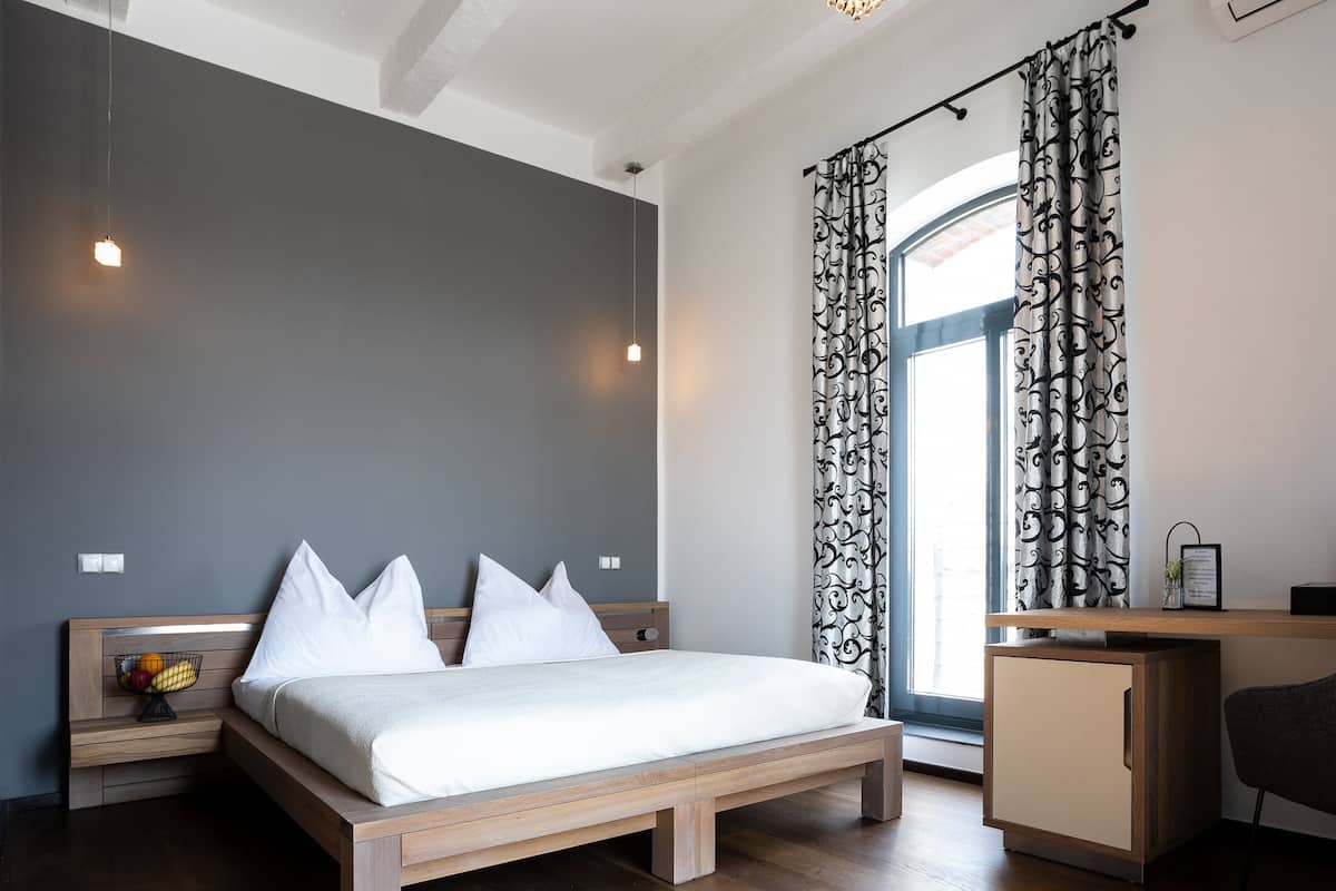 Quarto moderno com cama de madeira, mesa de cabeceira com frutas e escrivaninha com cadeira.