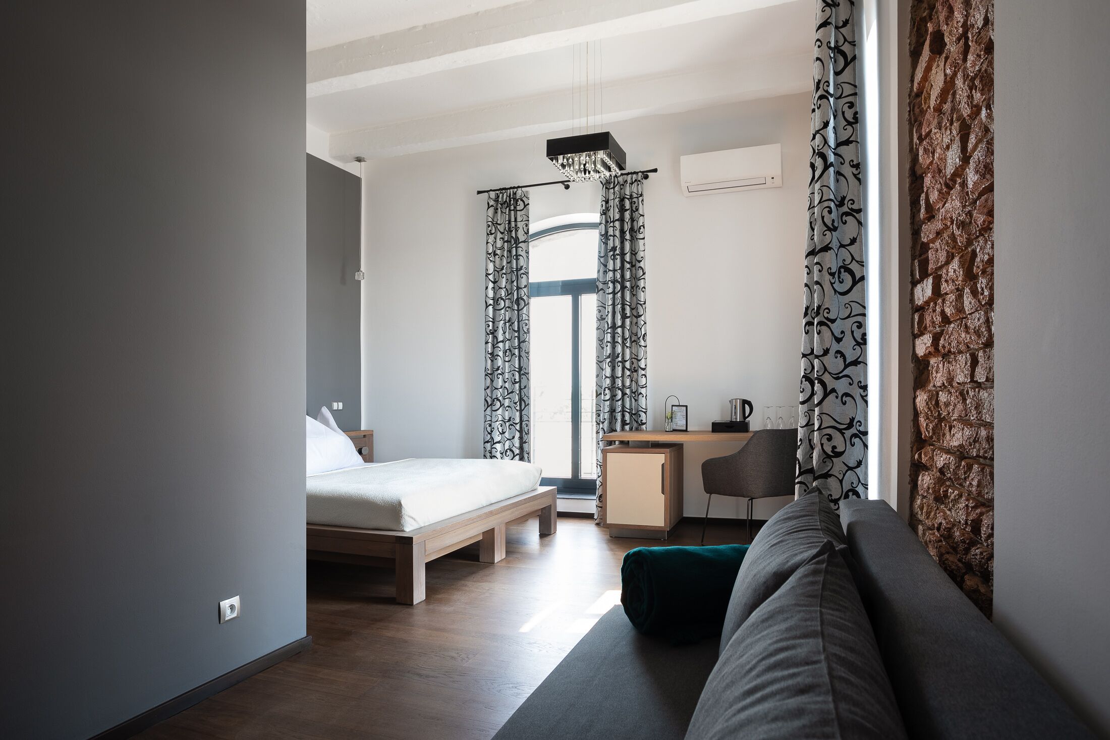 A modern hotel room with a bed, desk, and seating area.