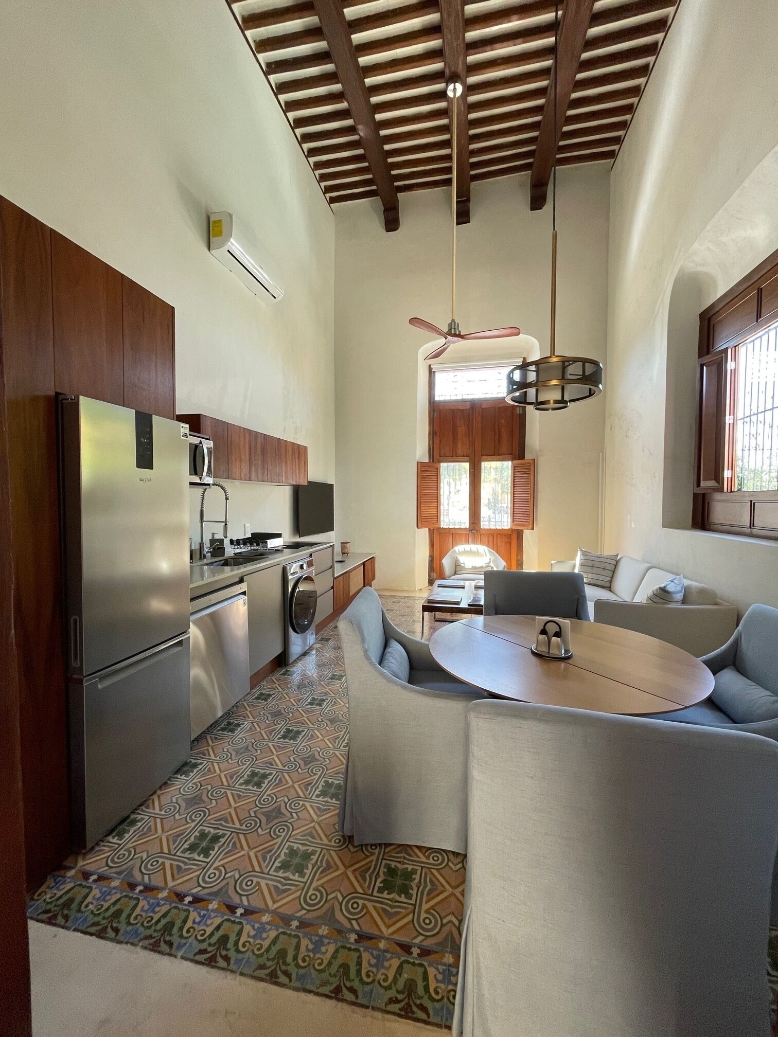 A compact kitchen with modern appliances, a dining area with a round table and chairs, and a ceiling fan.