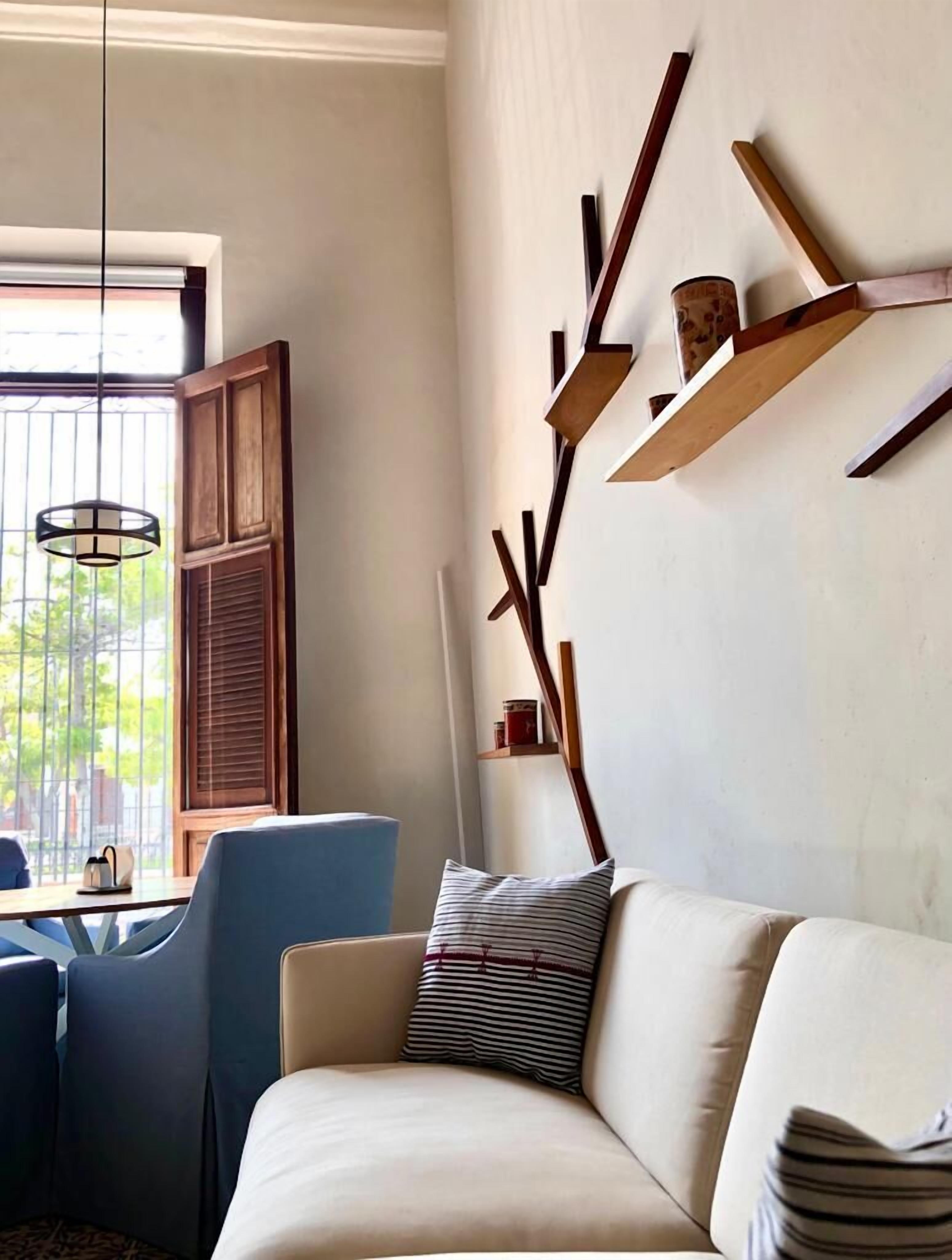 A modern living room with a sofa, a dining table with chairs, and a decorative wall piece.