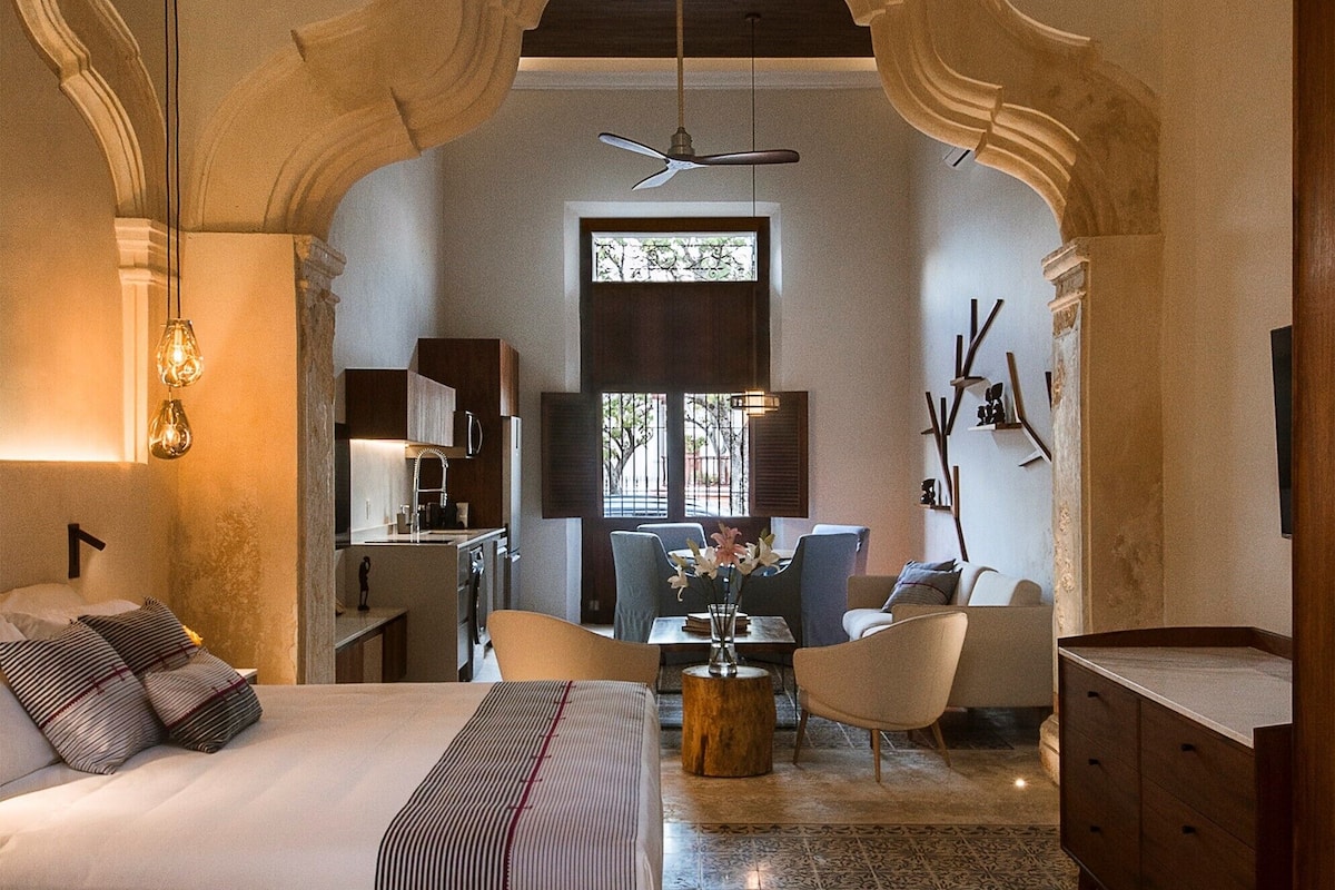 Un dormitorio amplio con una cama grande, zona de comedor y cocina.
