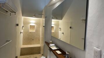 Une salle de bain moderne avec un grand miroir, un lavabo, des toilettes et un espace douche.