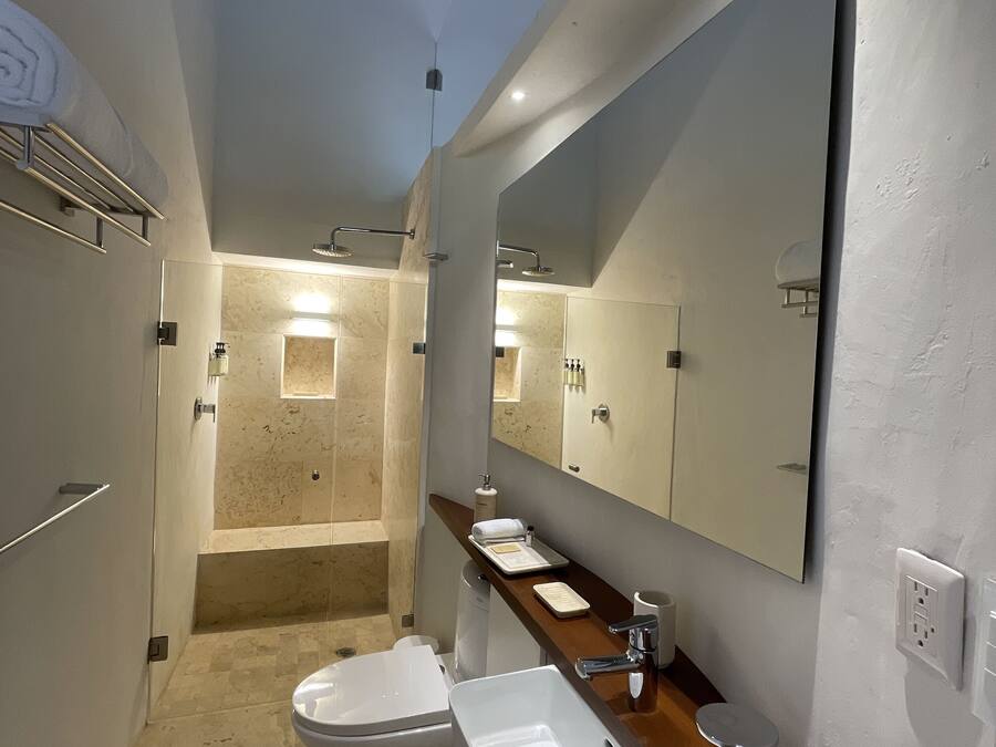 Une salle de bain moderne avec un grand miroir, un lavabo, des toilettes et un espace douche.