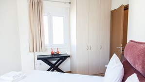 A hotel room with a bed, a desk, a window with curtains, and a wardrobe. - Great apt with amazing view in Koukaki (Athens)