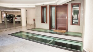 A modern lobby with a glass floor leading to a car parking area. - Great apt with amazing view in Koukaki (Athens)