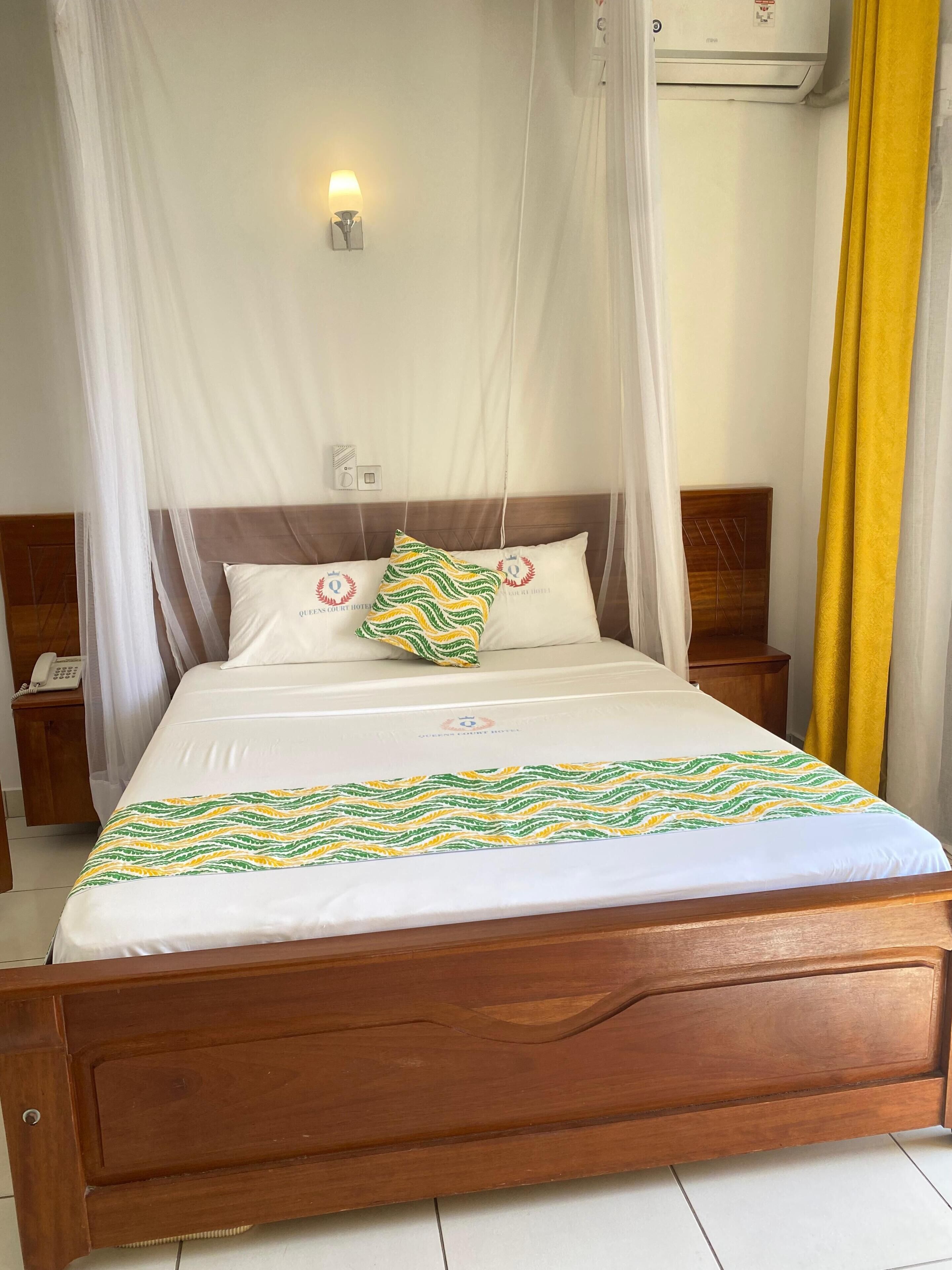 A bed with a canopy, a bedside phone, and a wall-mounted light fixture.