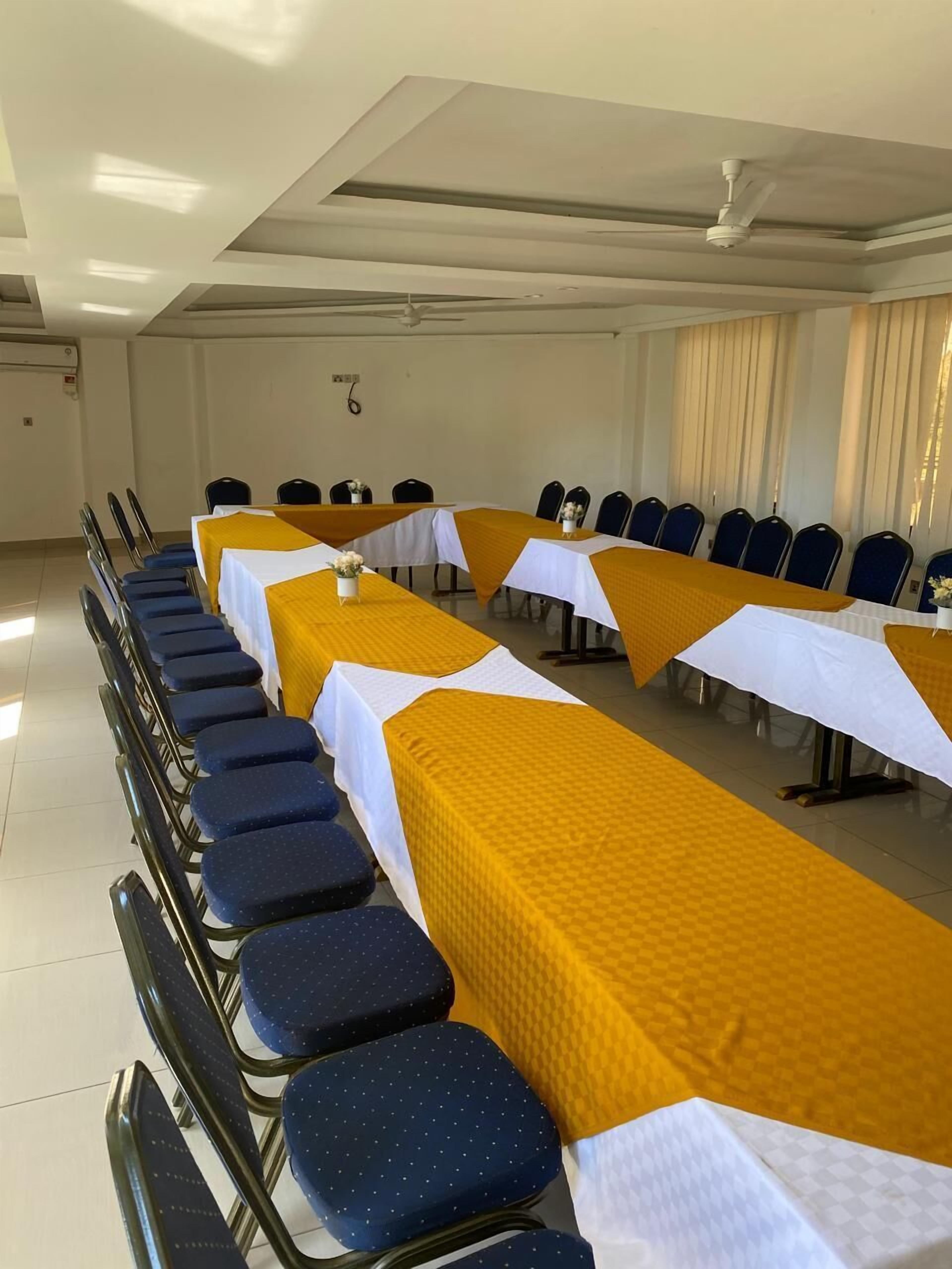 A conference room with long tables, chairs, and a ceiling fan.
