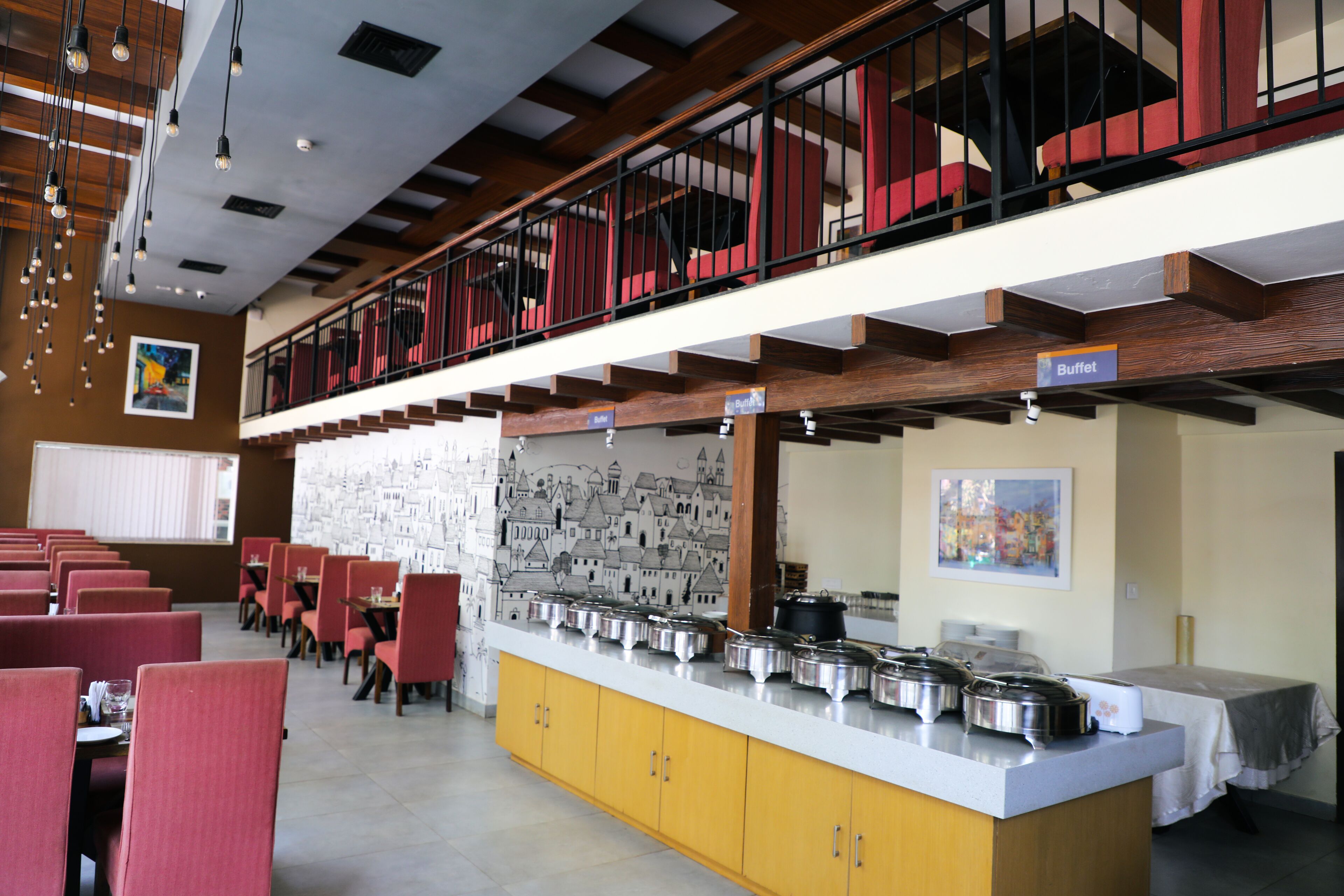 A buffet area with multiple serving stations, a counter with food containers, and a seating area with red chairs.