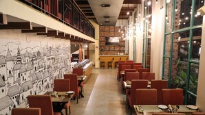 A restaurant with a long counter, red chairs, and a mural of a cityscape on the wall. - Rosetum Anjuna (Anjuna)