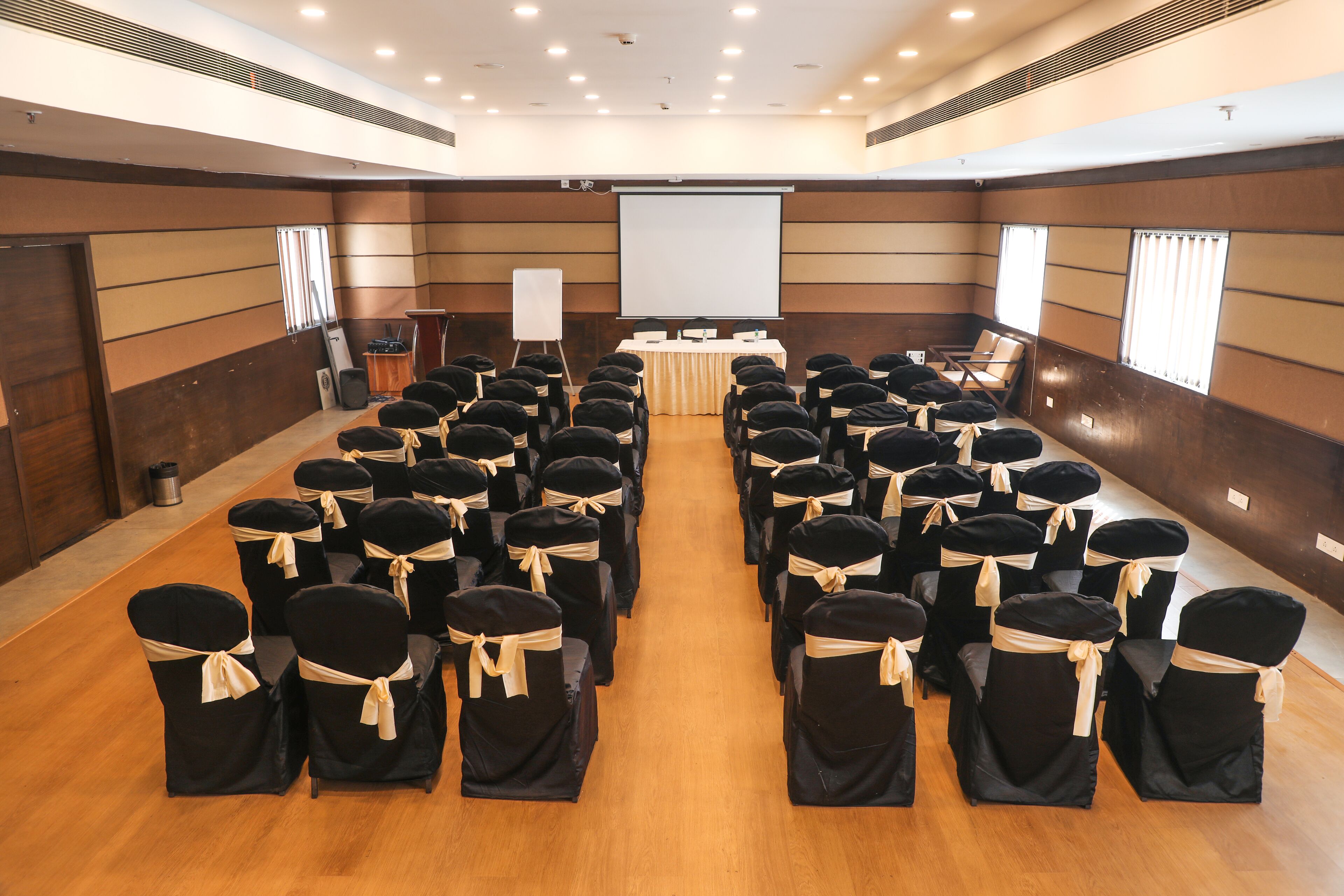 A conference room with rows of chairs, a podium, and a projector screen.