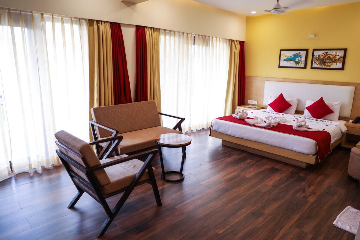 A hotel room with a bed, a sofa, a small table, and a chair.