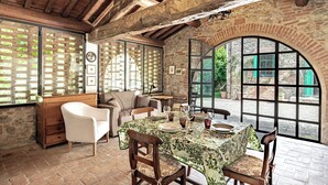 A rustic dining area with a brick wall, wooden ceiling beams, and a table set for four. - Studio With Pool And Orchard (Monteleone d'Orvieto)