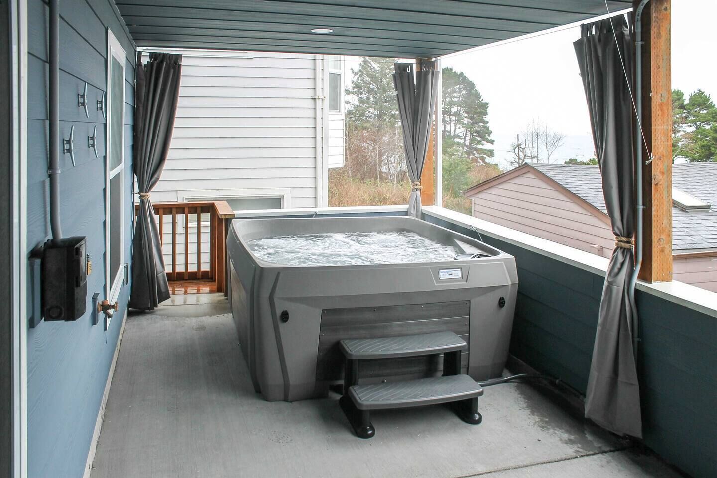 Een hottub in een overdekte buitenruimte, met uitzicht op een huis op de achtergrond.