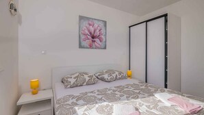 A bedroom with a bed, a nightstand, a lamp, a painting, and a sliding door.
