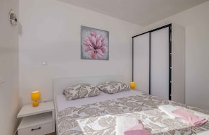 A bedroom with a bed, a nightstand, a lamp, a painting, and a sliding door.