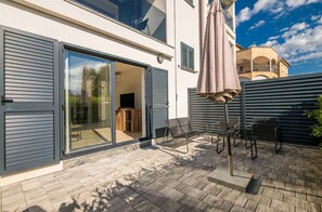 A modern house with a sliding glass door, outdoor seating, and a patio area.
