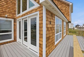 A wooden house with a deck, large windows, and a white exterior.