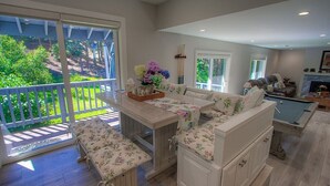 Amplia sala de estar con mesa de billar, un conjunto de sofás y una mesa de comedor con cojines estampados.