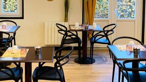 L'intérieur d'un restaurant, avec des tables, des chaises et une plante suspendue.
