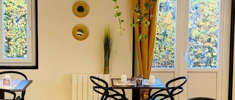 Interior de restaurante con mesas, sillas y una planta colgante.