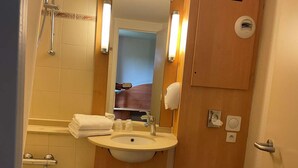 Une petite salle de bain comprenant un lavabo, un miroir, un porte-serviettes et une douche.