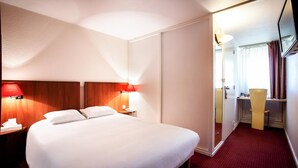 Une chambre d’hôtel avec un grand lit, deux tables de chevet avec des lampes, un bureau avec une chaise et un miroir.