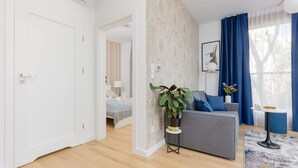 A modern living room with a grey sofa, a small round table, and a potted plant.