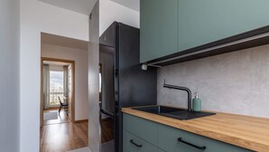 A modern kitchen with a black refrigerator, a wooden countertop, and green cabinets.