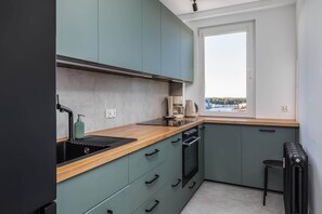A compact kitchen with a sink, stove, and a window overlooking a scenic view.