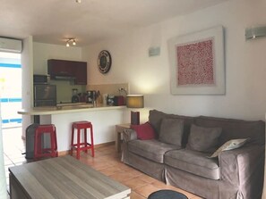 Um espaço compacto com cozinha compacta, sofá, mesa de jantar e uma parede vermelha de destaque.