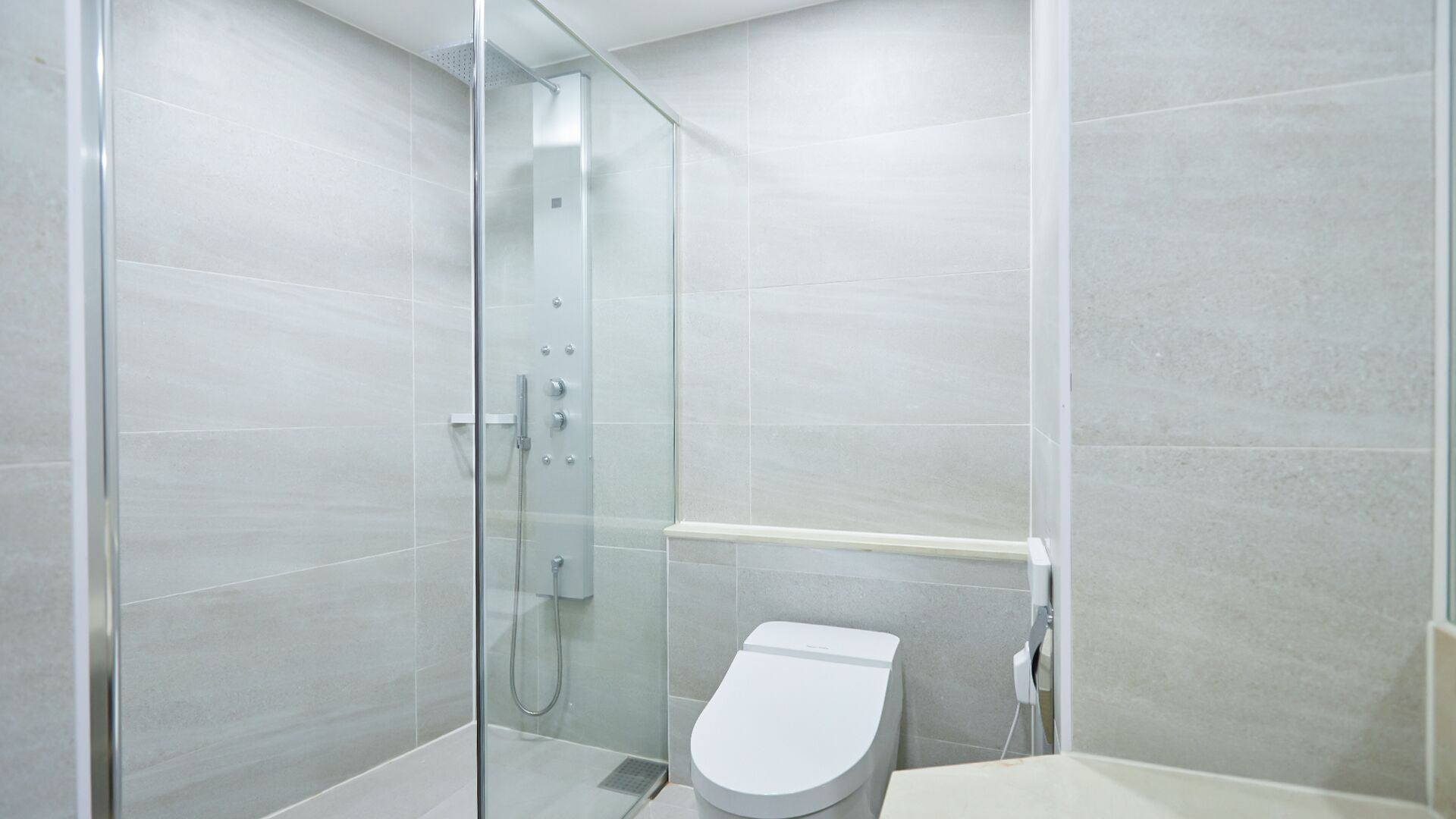 Un baño moderno con ducha acristalada, inodoro y lavamanos blancos.