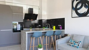 Una cocina moderna con una isla central, taburetes de bar, un sofá y una mesa de centro.