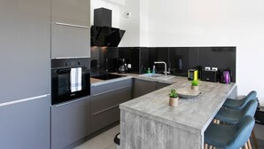 Una cocina moderna con electrodomésticos de acero inoxidable, una isla central y taburetes de bar.