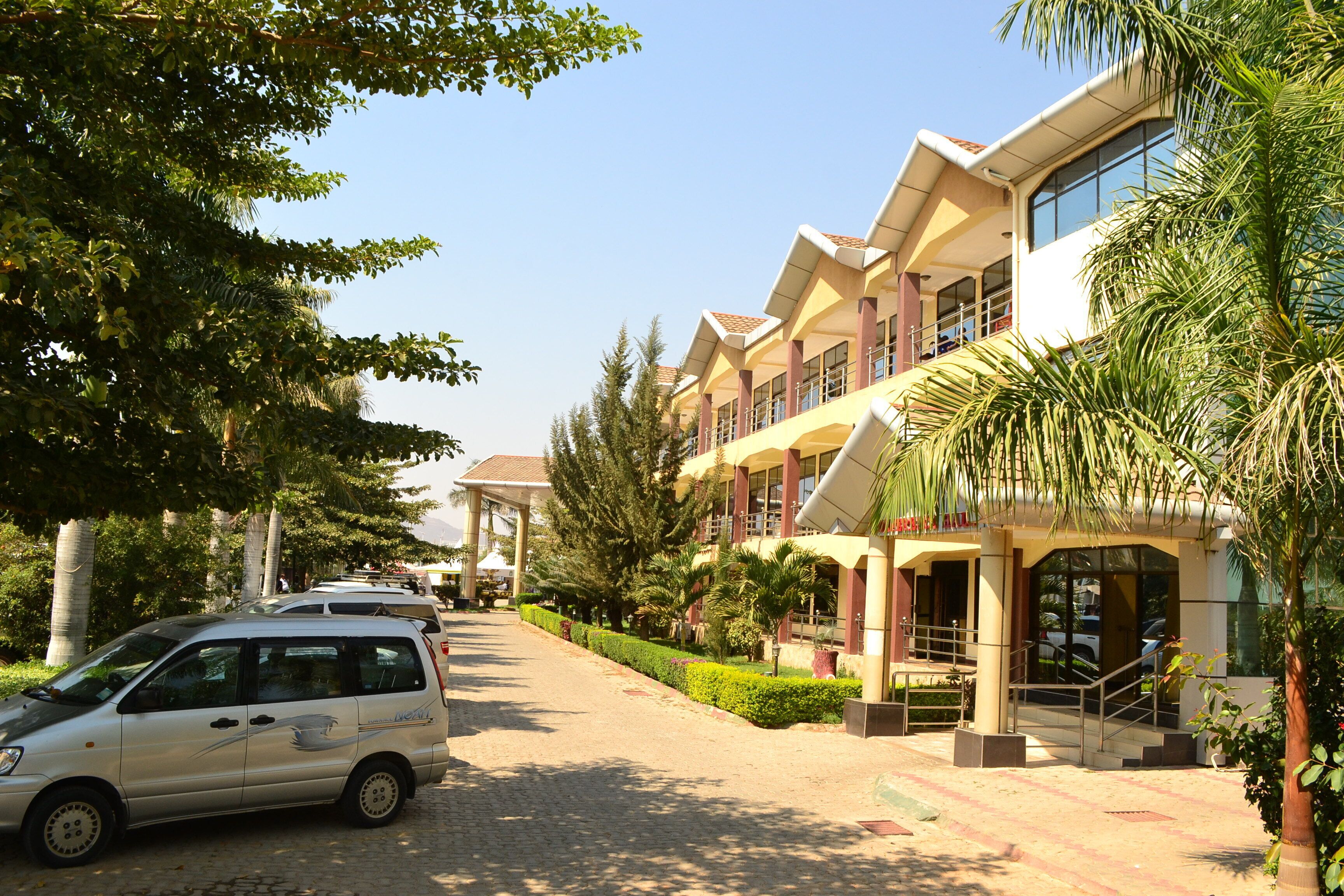 A multi-story hotel with a modern architectural design, featuring a central courtyard with a palm tree and a covered walkway.