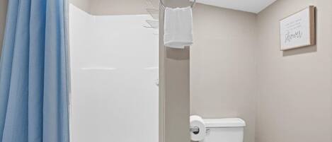 Een badkamer met douche, toilet en handdoekrek.