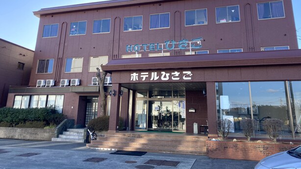 Ein Hotel mit einer braunen Fassade, zahlreichen Fenstern und einem Schild in Englisch und Japanisch.