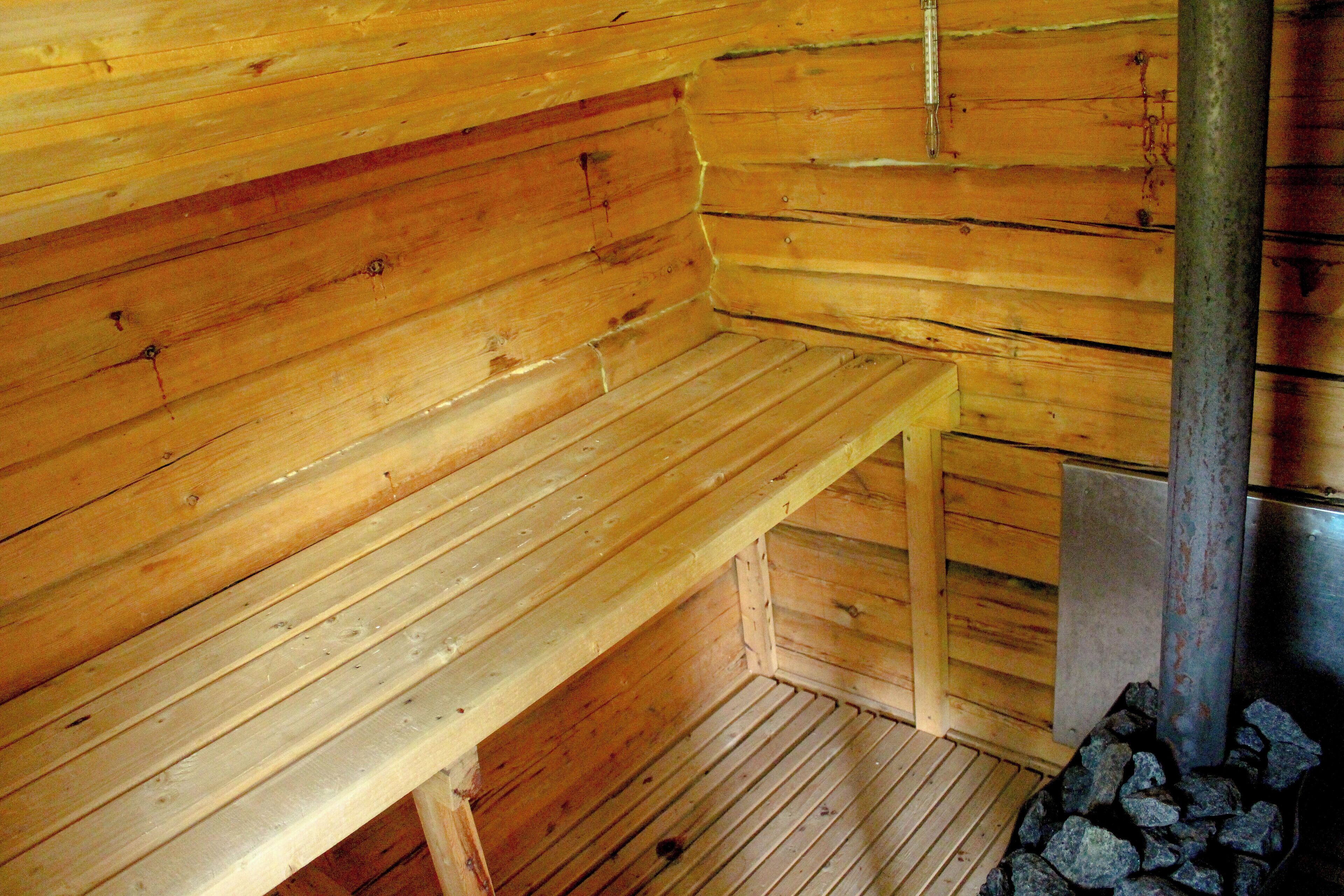 A wooden cabin interior with a bench and a fireplace.