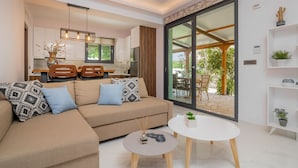 Een moderne woonkamer met een bank, salontafel en uitzicht op de keuken en terras.
