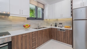 Een moderne keuken met witte kastjes, een roestvrijstalen koelkast en een marmeren aanrecht.