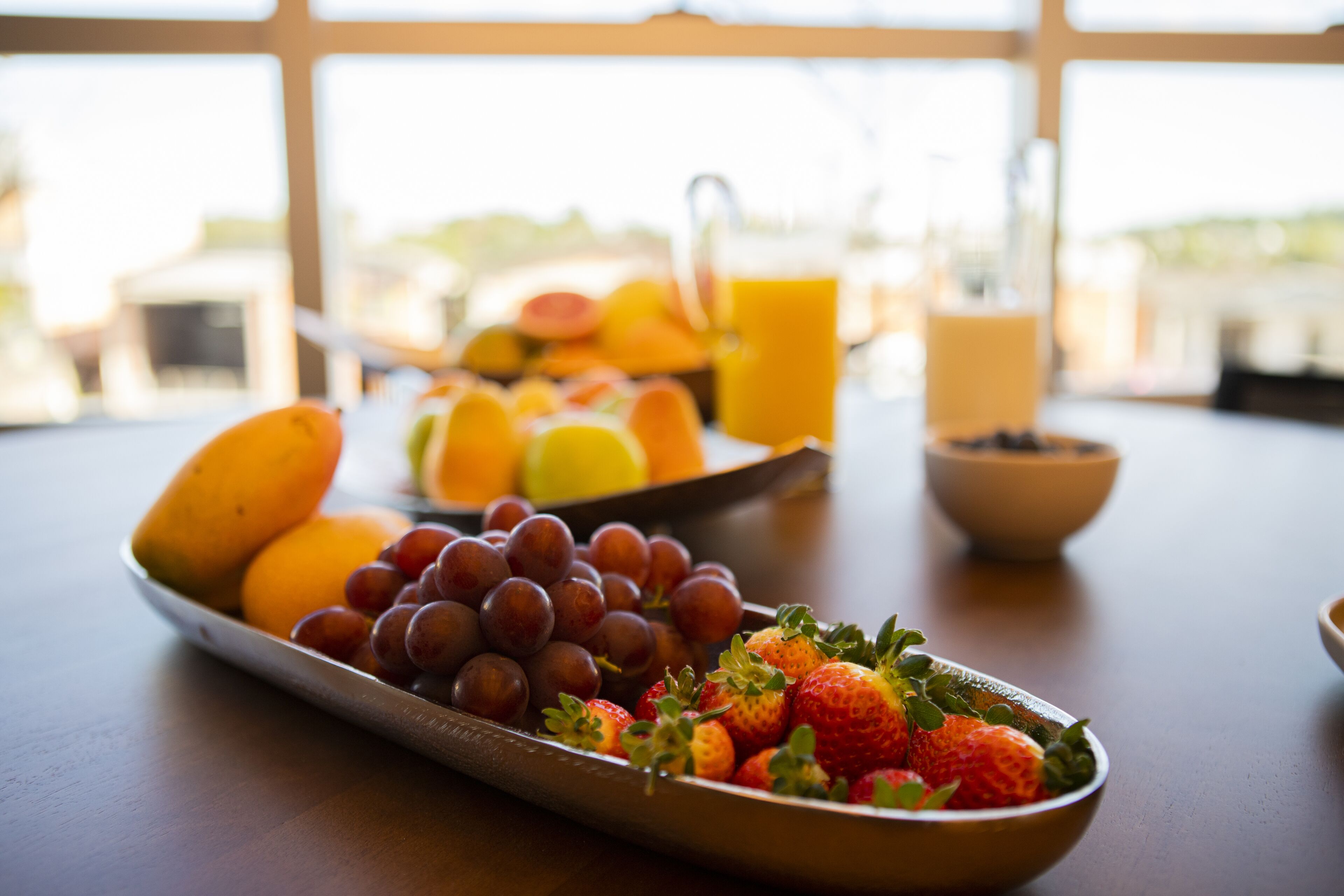 Una mesa de desayuno con diversas frutas y una jarra de jugo de naranja.