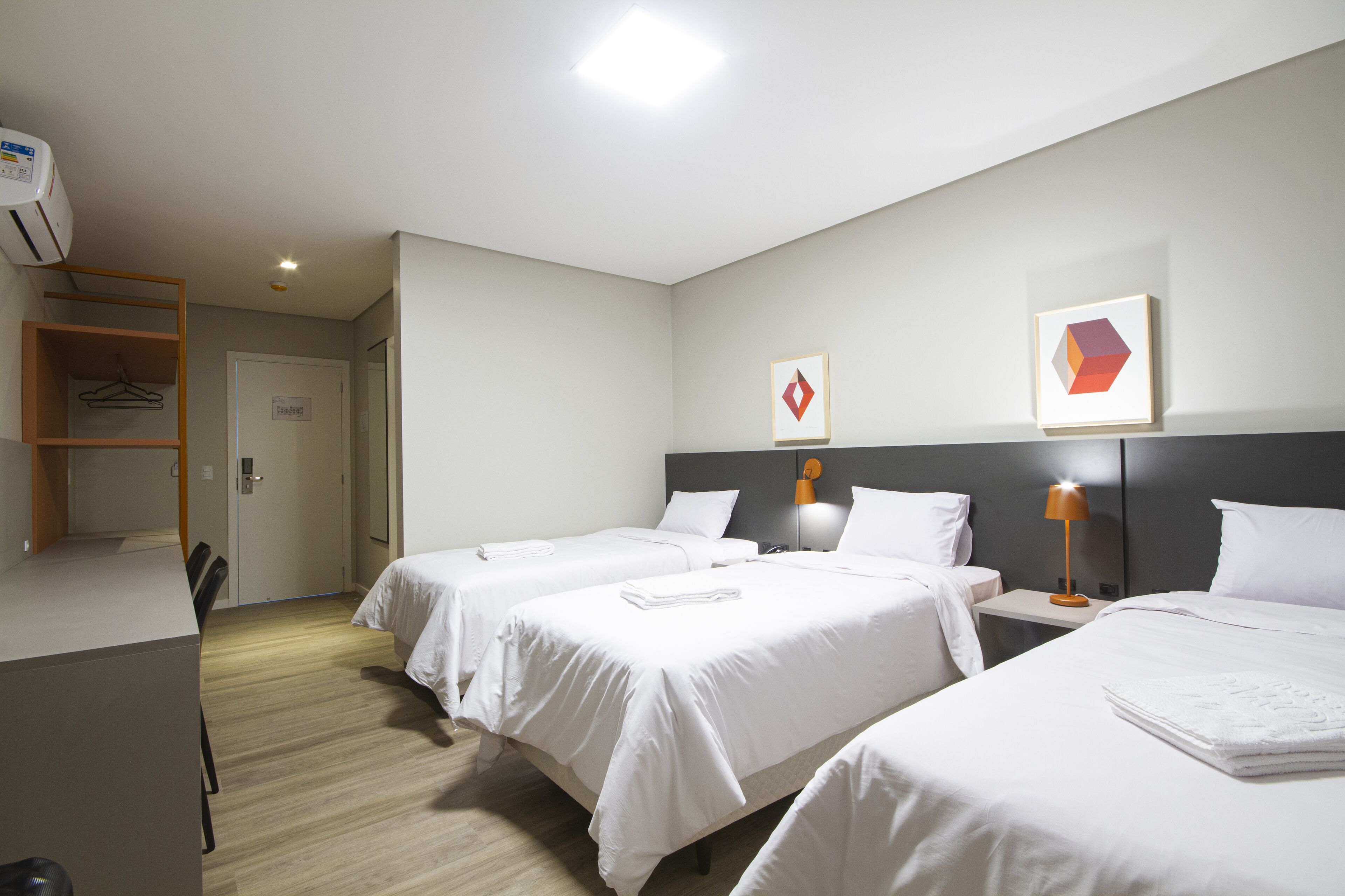 Habitación de hotel con dos camas, un escritorio y un armario.