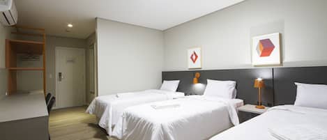 Habitación de hotel con dos camas, un escritorio y un armario.